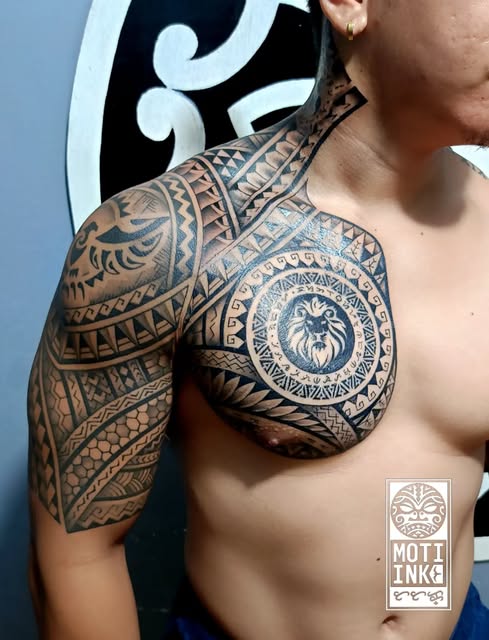 Polynesian and Filipino fusion chest and shoulder tattoo with a central lion medallion, by Miguel Lagbas / MOTI INK